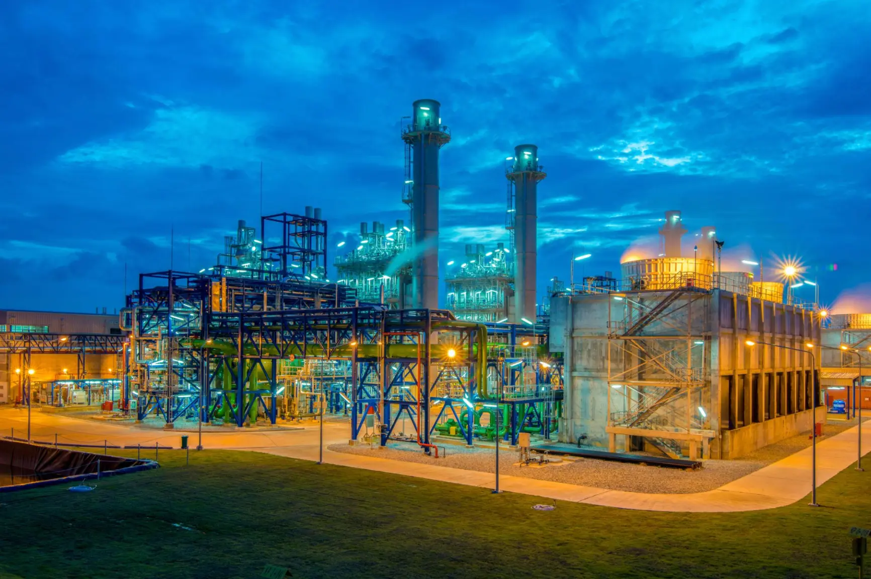 Combined-cycle plant at blue hour with cooling towers lit